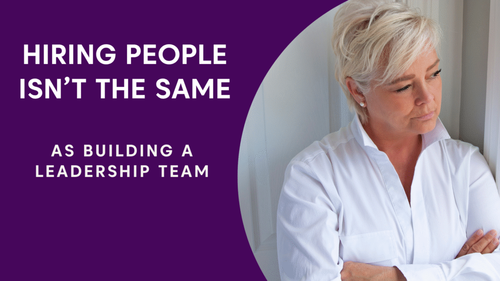 A thoughtful female founder looking out a window, illustrating the feeling of founder loneliness. The text overlay reads: 'Hiring people isn't the same as building a leadership team.'